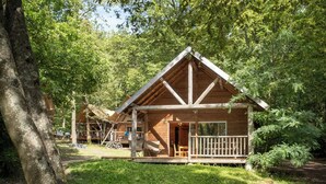 Une cabane en bois avec un porche, entourée d’arbres.
