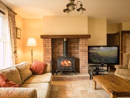 A living room with a brick fireplace, a sofa, a coffee table, a lamp, and a television.