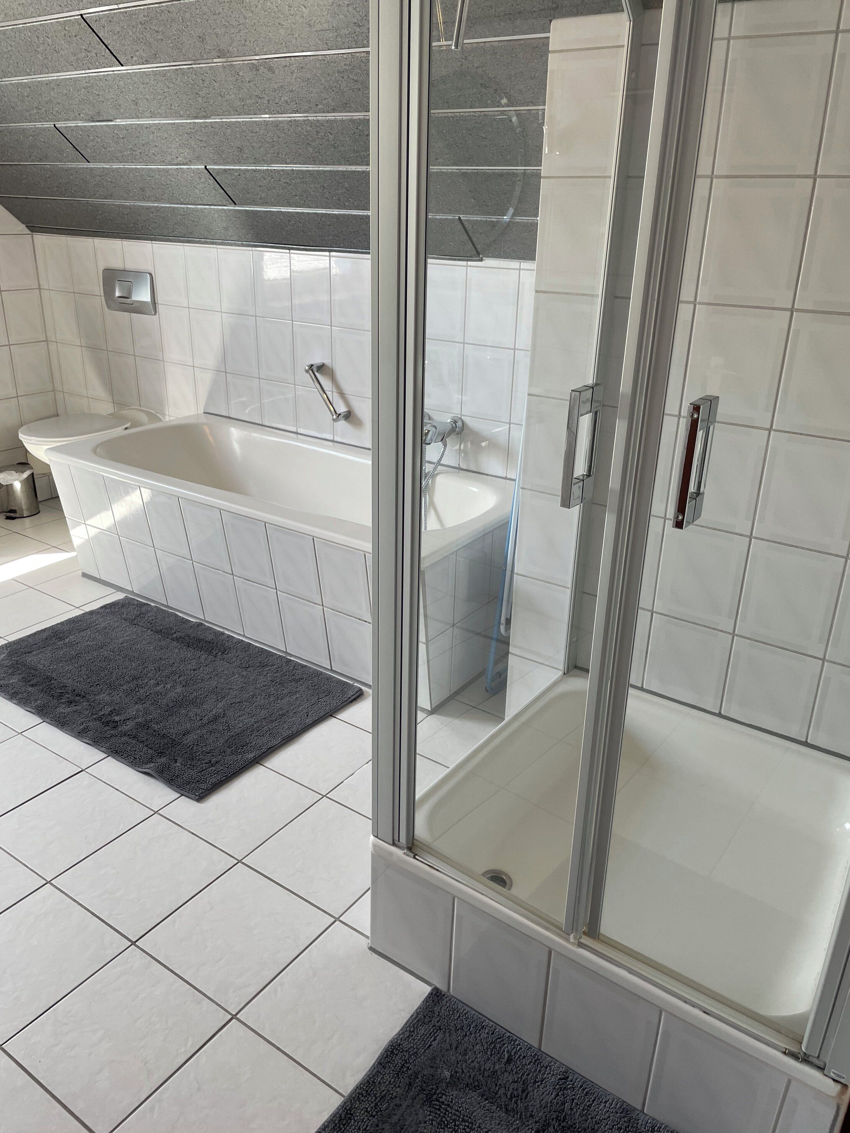 A modern bathroom with a glass-enclosed shower, a freestanding bathtub, and a white sink.