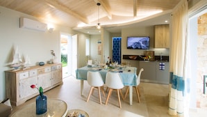 Un comedor con techo de madera, una mesa dispuesta para dos personas y un televisor al fondo.