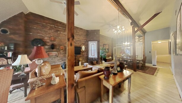 Un salon chaleureux avec un mur en briques, des meubles en bois et un lustre.