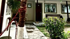 Una palmera con cocos, un camino de piedra y un edificio con ventanas y una puerta.