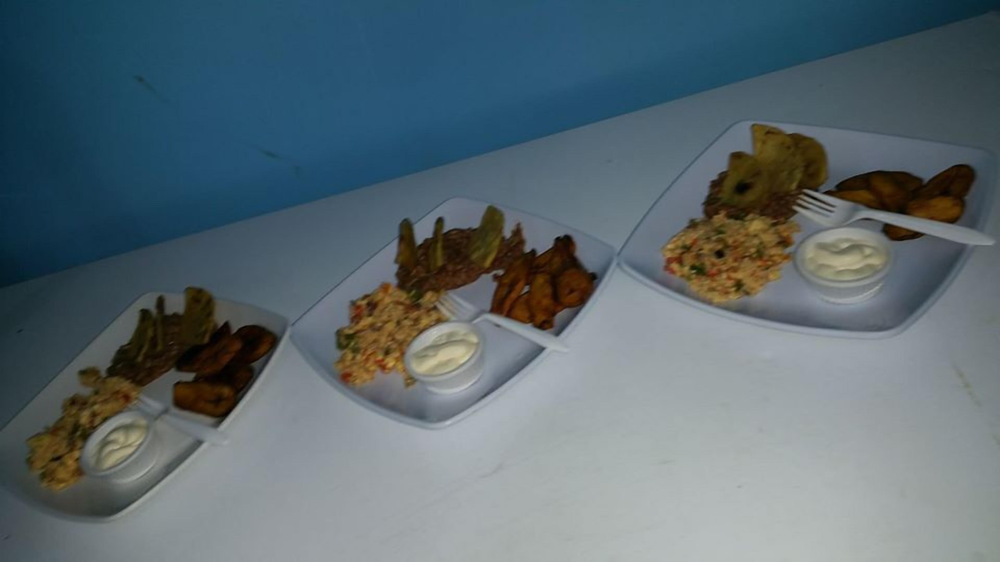 Three plastic plates with various food items including fried chicken, fries, and a salad with a side of sauce.