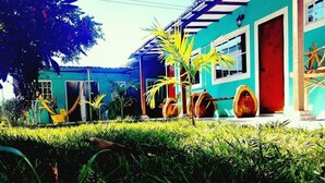 Una casa con fachada azul, puerta roja y un porche con barriles de madera.