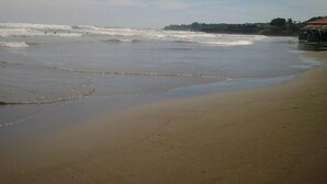 Una playa con olas, una cabaña y una costa distante.