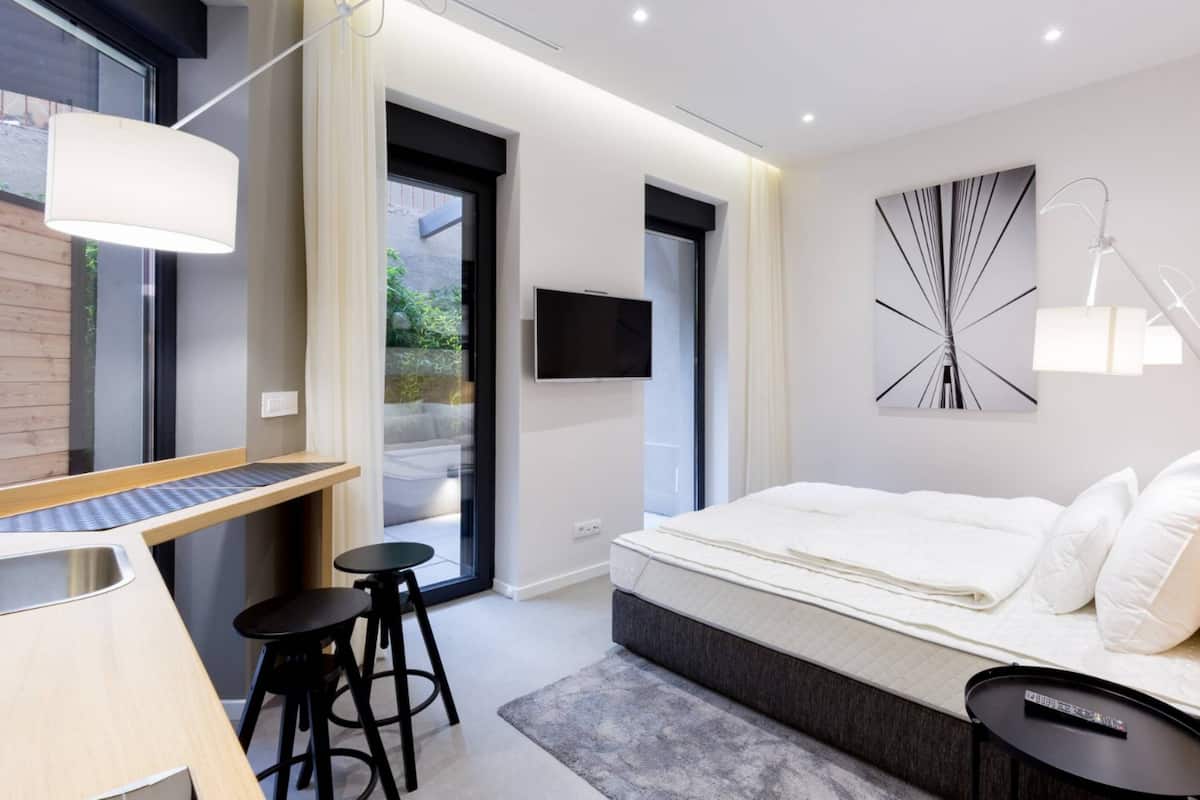Ein modernes Hotelzimmer mit einem Bett, einem Schreibtisch, zwei Stühlen, einem Fernseher und einem großen Fenster.