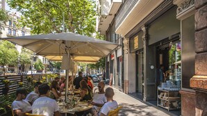An outdoor café with yellow chairs and a large umbrella, surrounded by buildings and trees. - Pedrera Suites - Habitat Apartments (Barcelona)