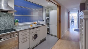 A modern kitchen with granite countertops, stainless steel appliances, and a built-in washer and dryer. - Pedrera Suites - Habitat Apartments (Barcelona)