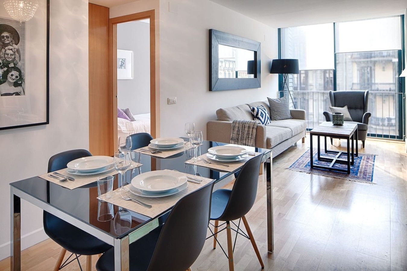 Un moderno comedor con una mesa de vidrio, sillas y un sofá al fondo.