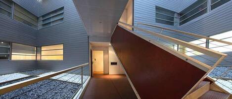 Un intérieur moderne avec un escalier central, une mezzanine et une vue sur l’extérieur.