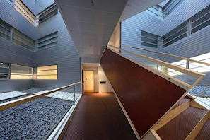 Un intérieur moderne avec un escalier central, une mezzanine et une vue sur l’extérieur.