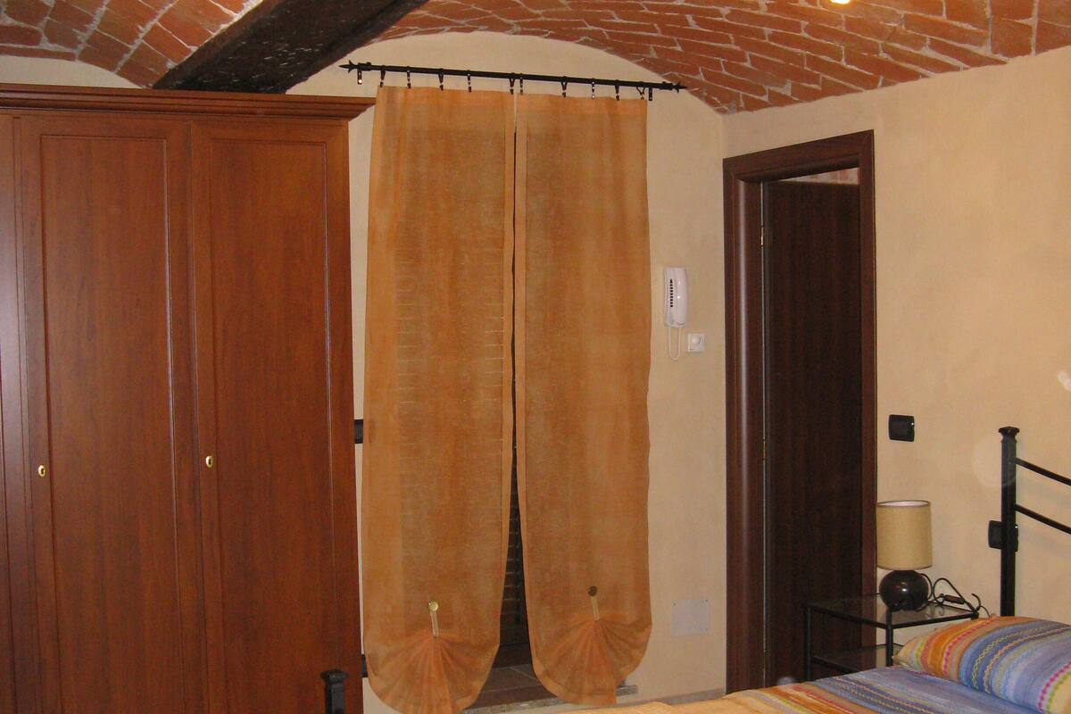 Un dormitorio con cama, armario de madera y techo de ladrillo.