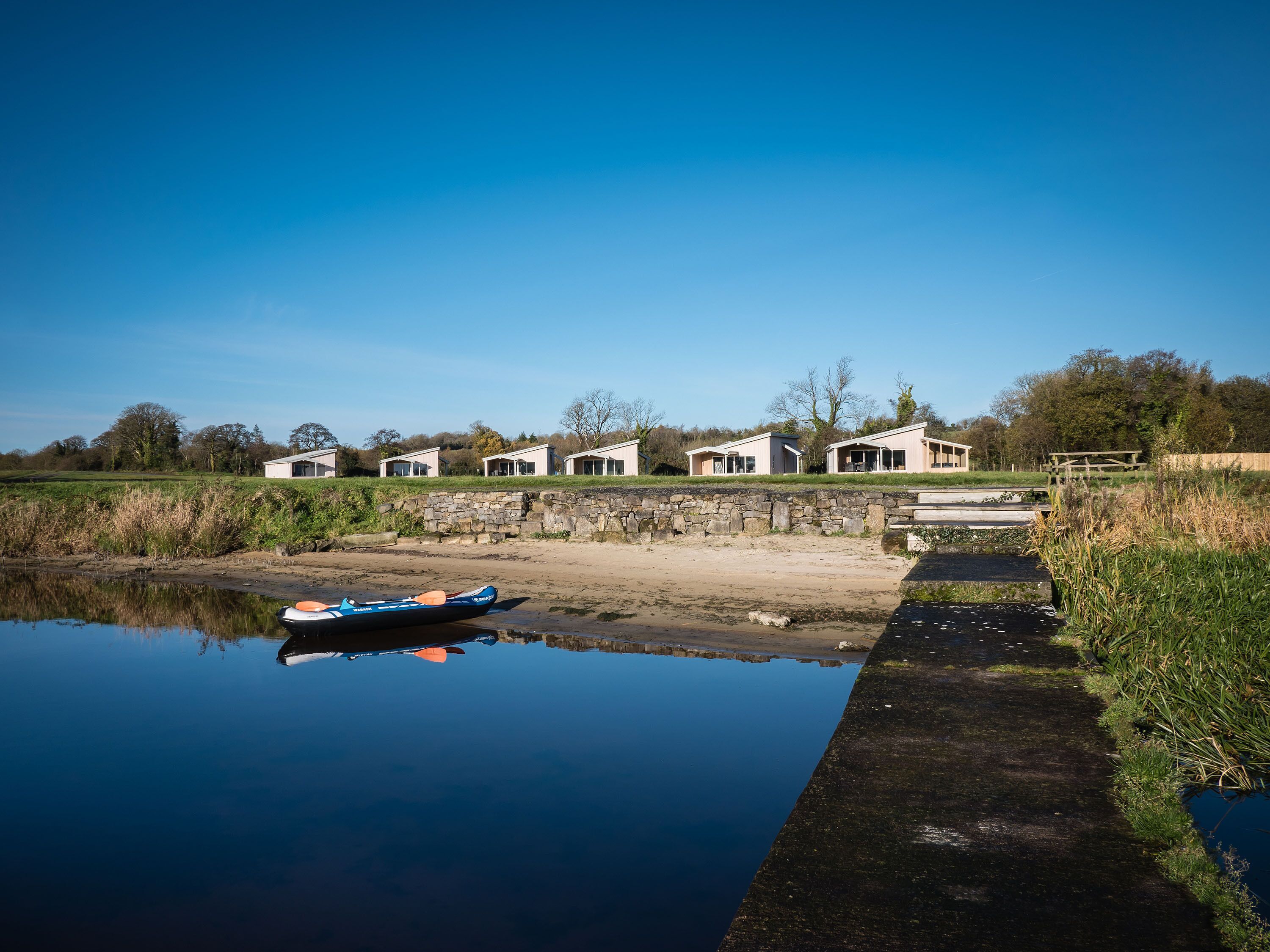 A row of white cottages with a canal in the foreground.