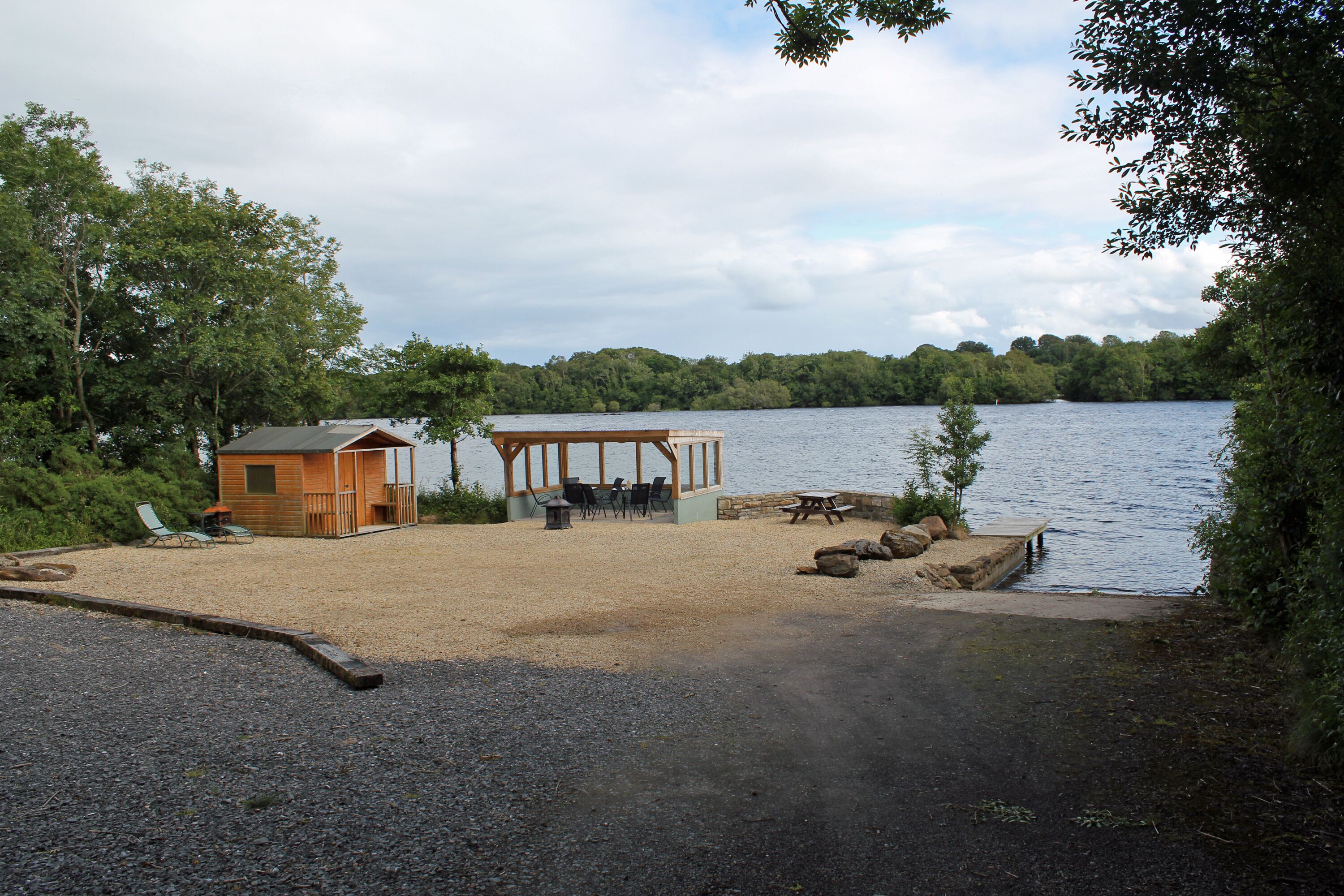 Una cabaña junto al lago con terraza y zona de estar al aire libre.
