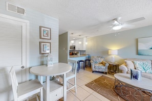 Relax in this open-plan living space with a dining table, sofa, and kitchen area featuring a countertop and microwave.