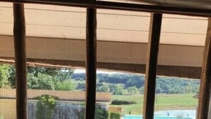Quarto com vista para uma piscina e jardim ajardinado.