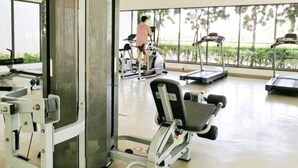 Une salle de sport équipée de matériel d’exercice, notamment des tapis de course et des appareils de musculation, et une personne utilisant un tapis de course.