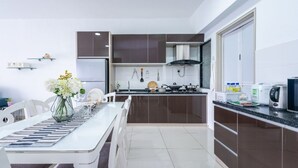 Une cuisine moderne avec un coin repas, comprenant une table blanche, un vase avec des fleurs et un plan de travail équipé d’appareils électroménagers.