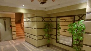A lobby with a geometric floor pattern, a staircase, and potted plants. - Superior Luxury Furnished Apartment (Cairo)