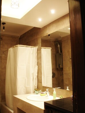 Bañera con ducha, toallas, jabón, shampoo