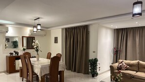 A modern living room with a dining area, featuring a sofa, a coffee table, and a dining table with chairs. - Superior Luxury Furnished Apartment (Cairo)