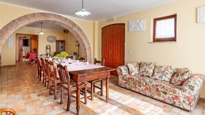 A dining area with a brick archway, wooden table, and chairs. - Agriturismo La Macinara (Perugia)