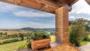 A rustic outdoor area with a brick column, a wooden bench, and a potted plant. - Agriturismo La Macinara (Perugia)