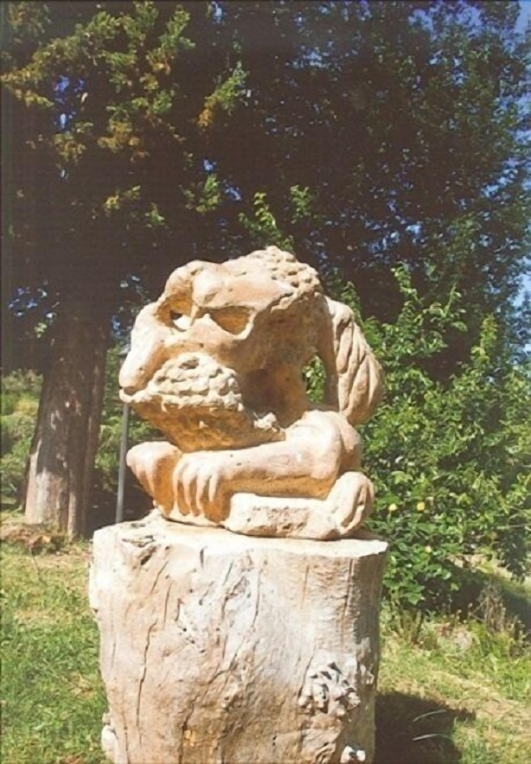 Una escultura de piedra que representa una figura sentada sobre un tocón de árbol.
