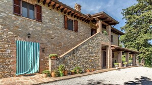 A stone building with a wooden staircase leading to a covered porch. There are potted plants along the steps and a striped towel hanging on the wall. - Agriturismo La Macinara (Perugia)