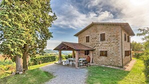 A stone house with a covered patio and a gravel driveway. - Agriturismo La Macinara (Perugia)