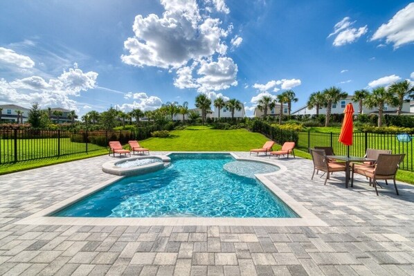Relax by the pool surrounded by lush greenery and palm trees.