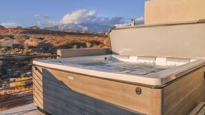A hot tub on a rooftop with a view of a desert landscape.