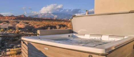 A hot tub on an outdoor deck with a view of a mountainous landscape.
