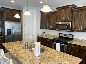A kitchen with granite countertops, stainless steel appliances, and dark wooden cabinets. - Oversized Private Hot Tub with XBOX (Washington)