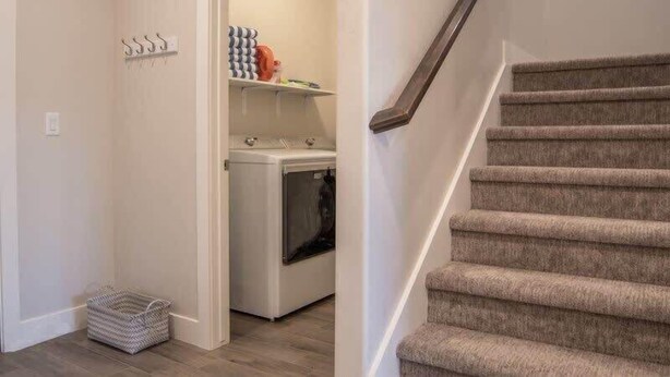 A laundry area with a washing machine, a drying rack, and a basket.