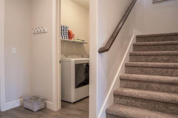 A laundry area with a washing machine, a drying rack, and a basket.