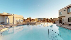 A swimming pool with a clear view of the surrounding buildings and a landscaped area with palm trees. - Oversized Private Hot Tub with XBOX (Washington)