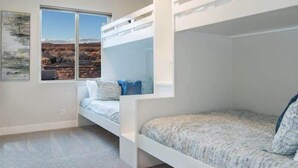 A bedroom with bunk beds, a large window with a view of a desert landscape, and a framed picture on the wall.