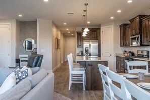 A modern kitchen with dark wooden cabinets, stainless steel appliances, and a central island with seating. - Oversized Private Hot Tub with XBOX (Washington)
