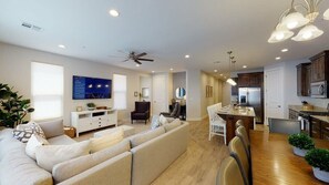 Un salon moderne avec un canapé, un téléviseur et un coin repas.