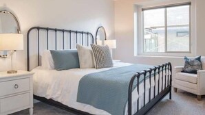 A bedroom with a bed, bedside tables, a chair, and a window. - Oversized Private Hot Tub with XBOX (Washington)