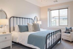 A bedroom with a bed, bedside tables, a chair, and a window. - Oversized Private Hot Tub with XBOX (Washington)
