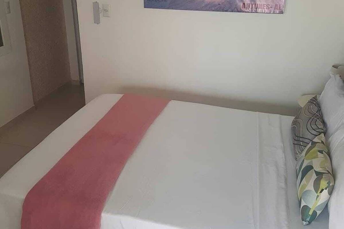 A bedroom with a bed, a painting, and a door.