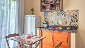 A compact kitchen with a refrigerator, wooden cabinets, and a tiled backsplash. - I9 Embau Flats & Suites (Itacaré)