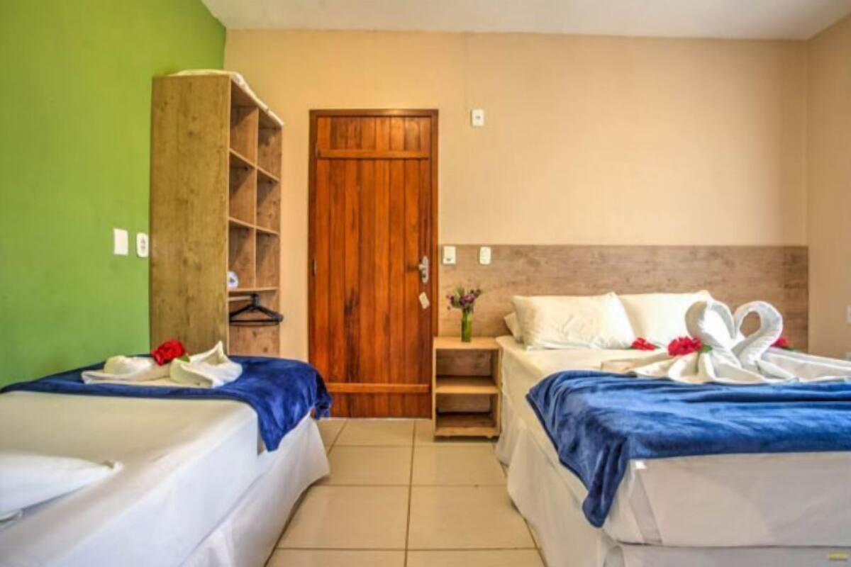 Ein Hotelzimmer mit zwei Betten, einem Holzschrank und einem kleinen Tisch mit einer Vase.