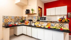 A kitchen with white cabinets, a black countertop, and a colorful tile backsplash. - I9 Embau Flats & Suites (Itacaré)