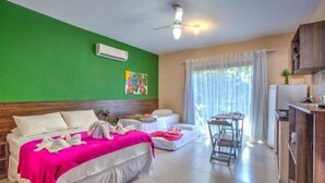 A hotel room with a bed, a sofa, a dining table, and a kitchenette. - I9 Embau Flats & Suites (Itacaré)