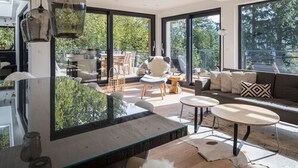 A modern living room with a glass coffee table, a sofa, and a dining area with chairs. - Schweizerhaus Alpirsbach (Alpirsbach)