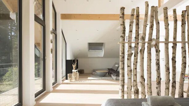 A modern bedroom with a large window, a bed with a white headboard, and a birch tree wall. - Schweizerhaus Alpirsbach (Alpirsbach)