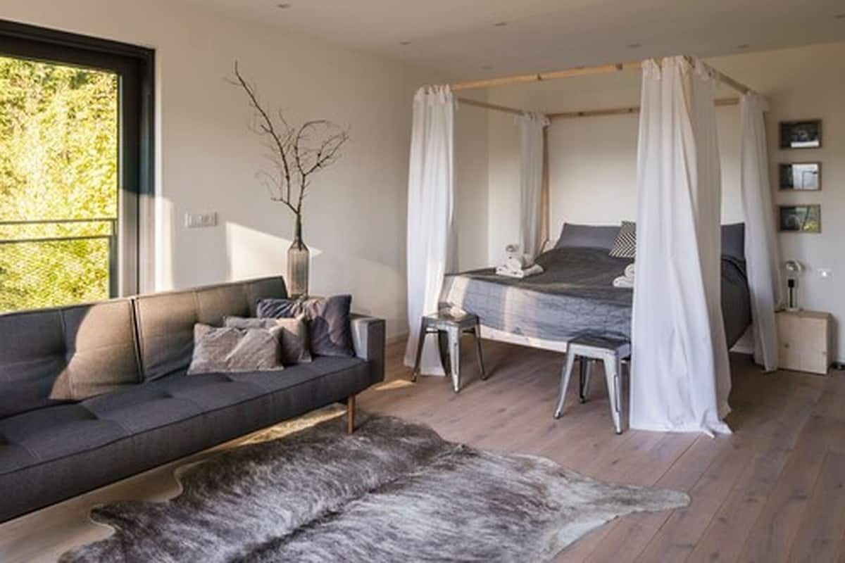 Une chambre à coucher moderne avec un lit, un canapé, un petit tabouret et un tapis en fourrure.